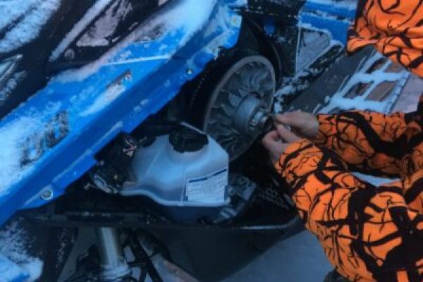 A person fixing a snowmobile in the snowy Sweden