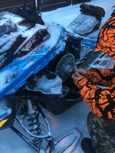 A person fixing a snowmobile in the snowy Sweden